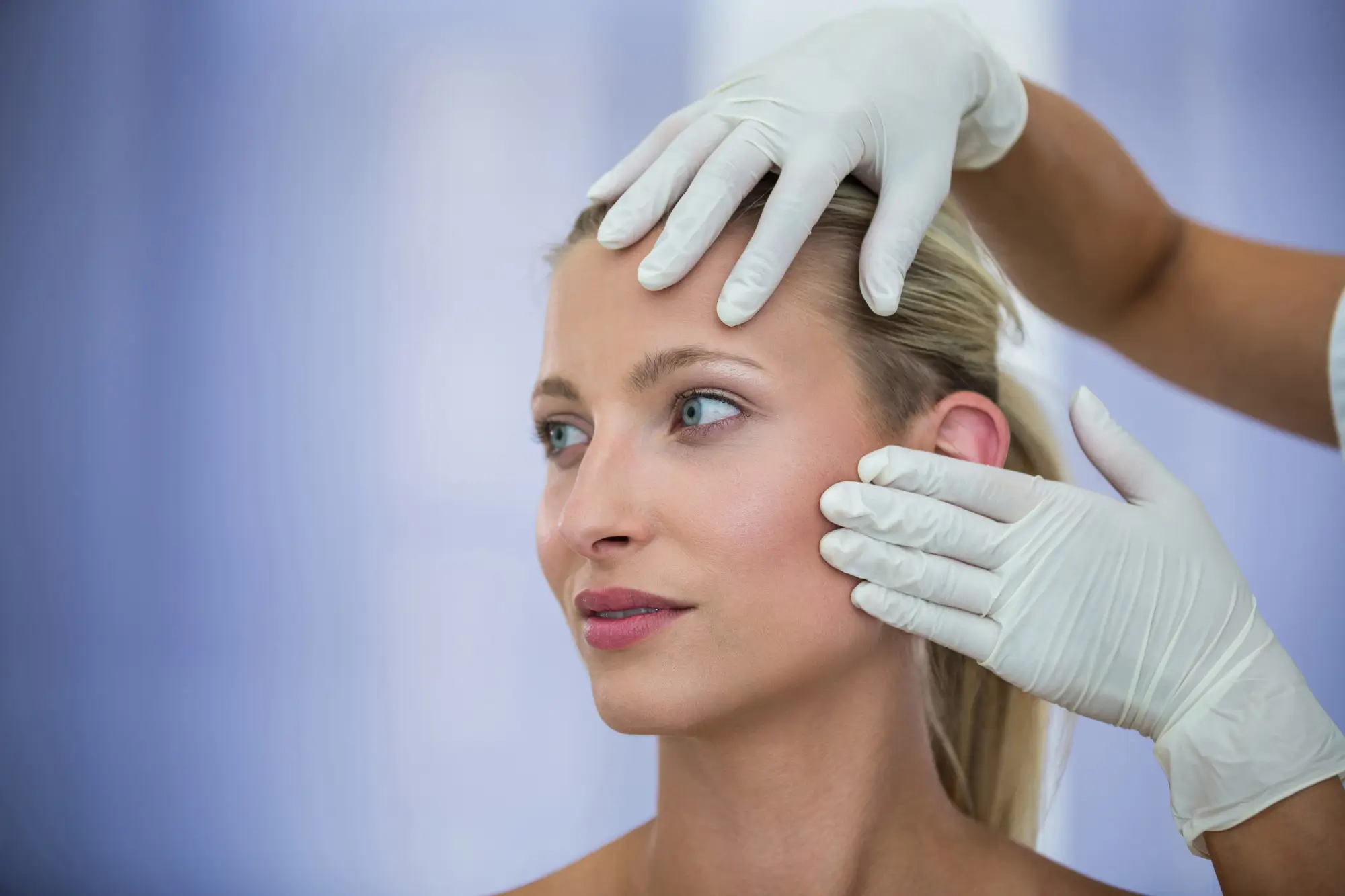Doctor examining female patients face from cosmetic treatment Doctor examining female patients face from cosmetic treatment